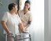 Smiling nurse helping senior lady to walk around the nursing home