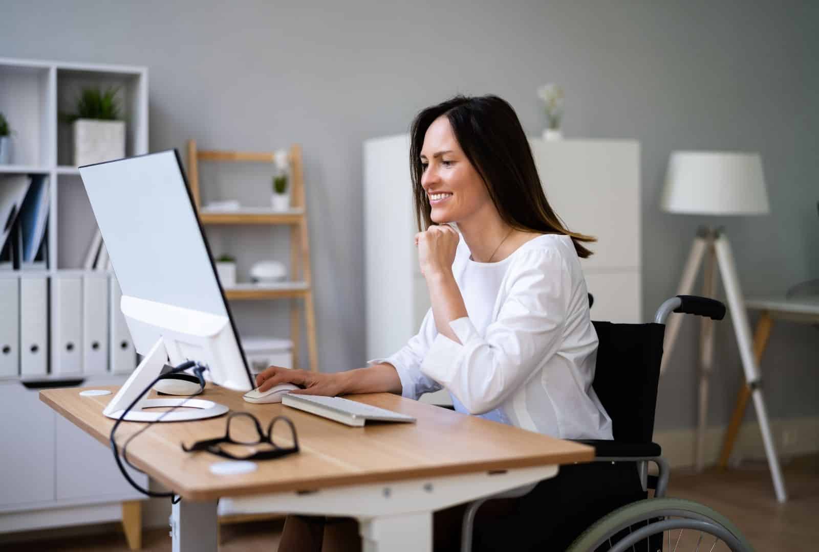 אישה נכה בכיסא גלגלים עובדת במחשב משרד נגיש – חיסכון בפטור אגרת רישוי עם תו נכה